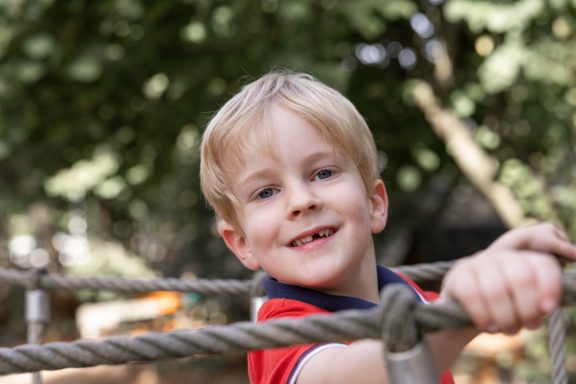 Kleiner Junge lächelt bei einem Outdoor-Fotoshooting in die Kamera