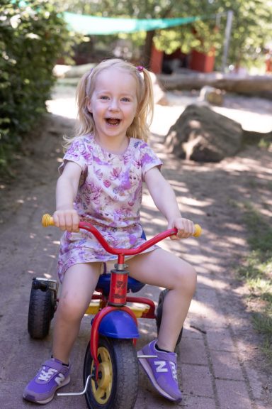 Mädchen auf einem Kinderfahrrad beim Spielen draußen