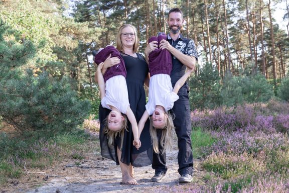 Familienfotografie mit Spaß Vier Familienmitglieder posieren spielerisch im Freien, zwei davon kopfüber.