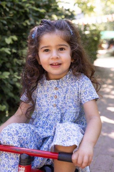 Fröhliches Mädchen im blauen Kleid bei einem Outdoor-Fotoshooting
